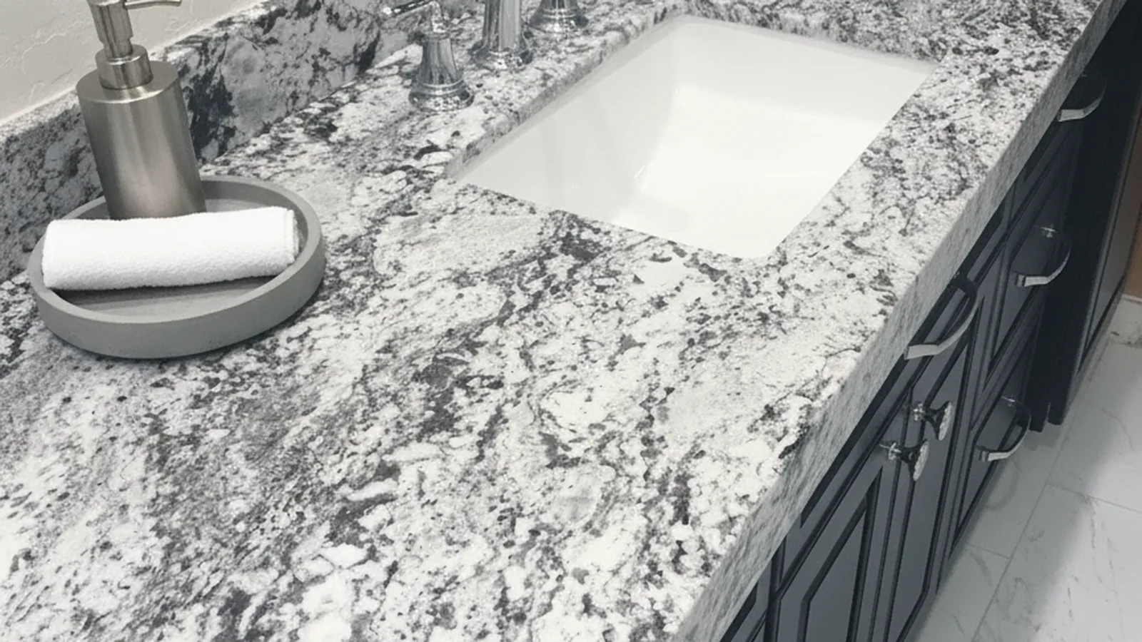 Close-up of a stone vanity top with an undermount sink and brushed nickel faucet